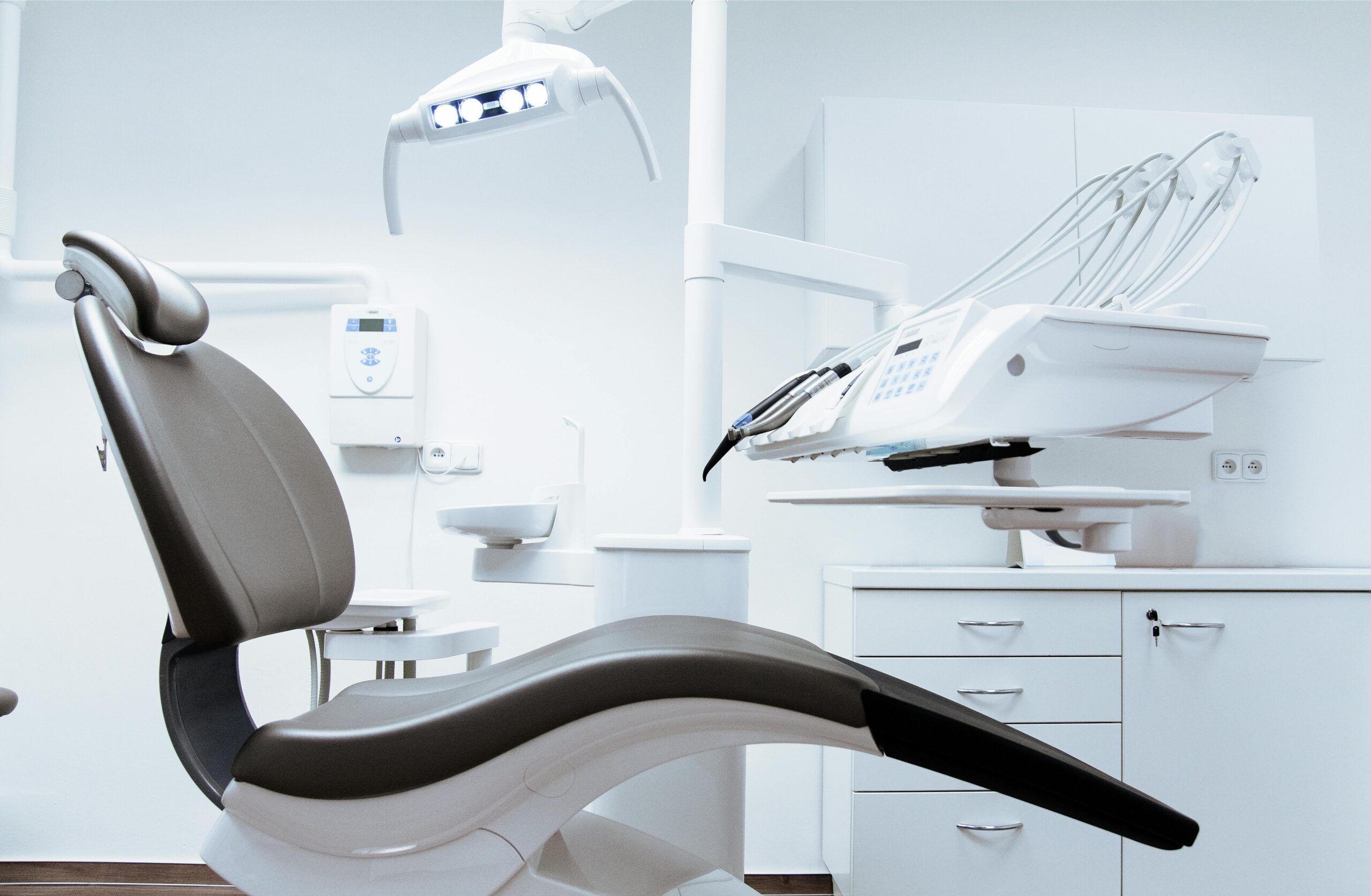 A modern dental clinic interior showcasing a dental chair and equipment in a clean, clinical setting.