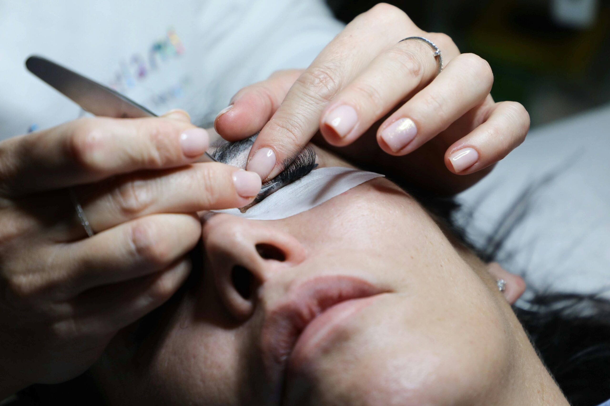 Detailed close-up of a woman receiving eyelash extensions in a professional beauty salon.